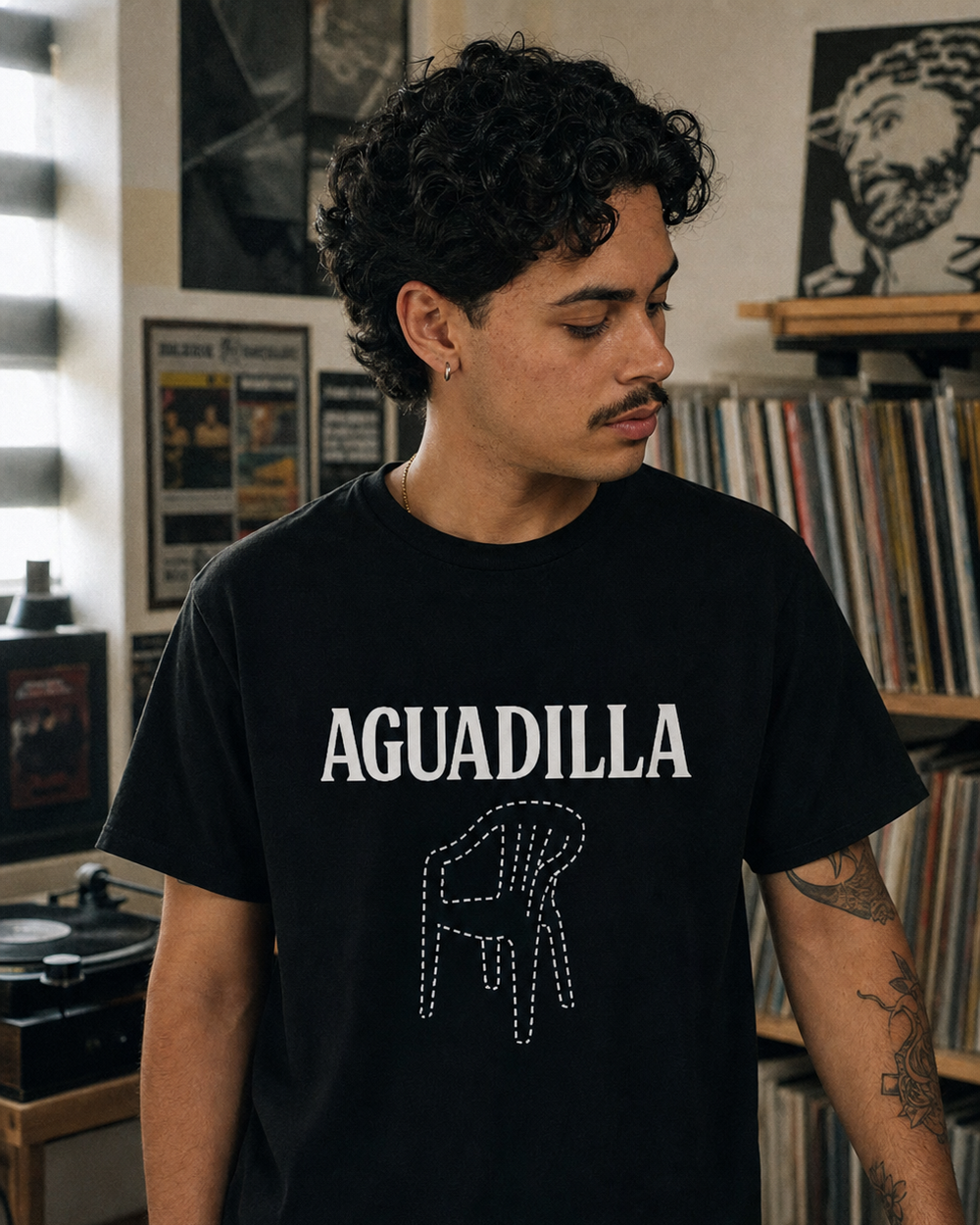 Puerto Rican adult wearing AGUADILLA Chair T-Shirt - El que se va pa' Aguadila pierde su silla in a relaxed creative setting