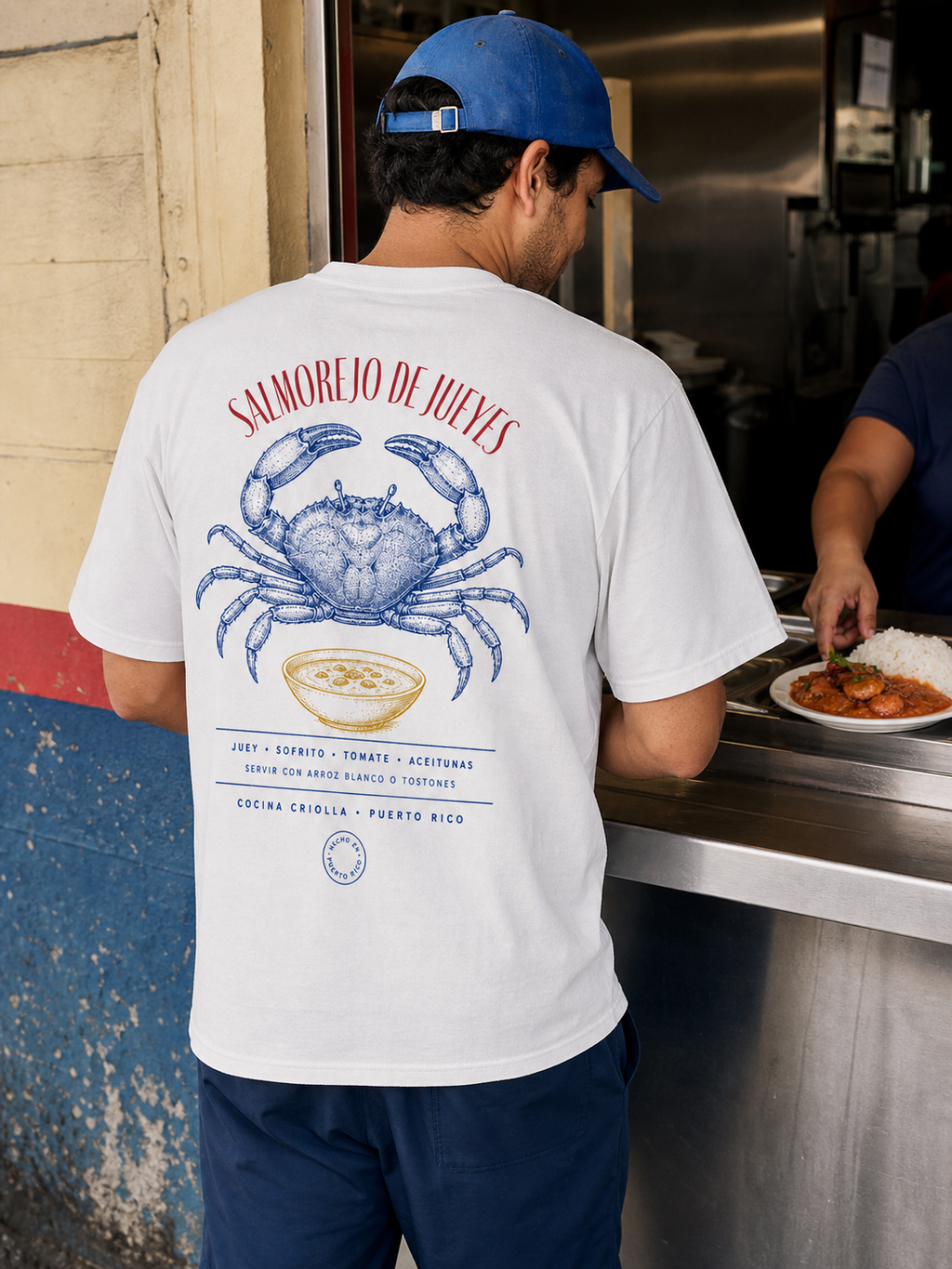 Man wearing the Salmorejo de Jueyes T-shirt at a Puerto Rican food counter