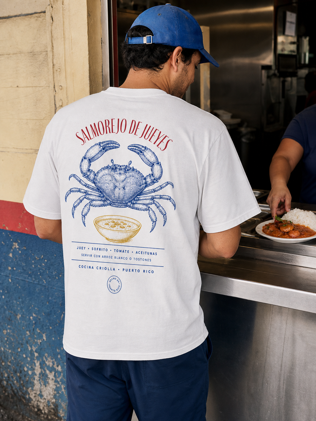 Man wearing the Salmorejo de Jueyes T-shirt at a Puerto Rican food counter